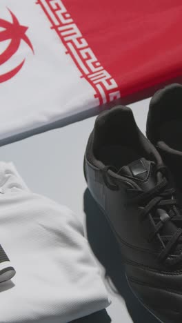 Vertical-Video-Studio-Still-Life-Shot-Of-Football-Soccer-Boots-Iranian-Flag-Shirt-And-Shorts-And-Captains-Armband-